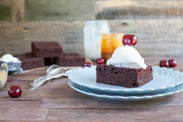 A serving of gluten free chocolate brownie topped with vanilla ice cream.