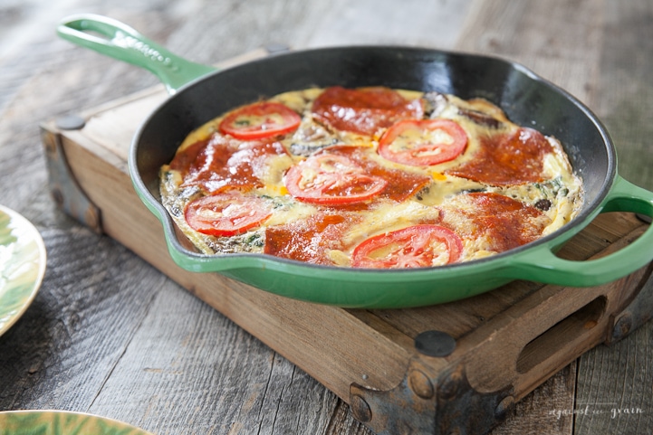 A skillet of Gluten Free, Paleo Pizza Frittata filled with mushrooms, spinach, tomatoes, and pepperoni.