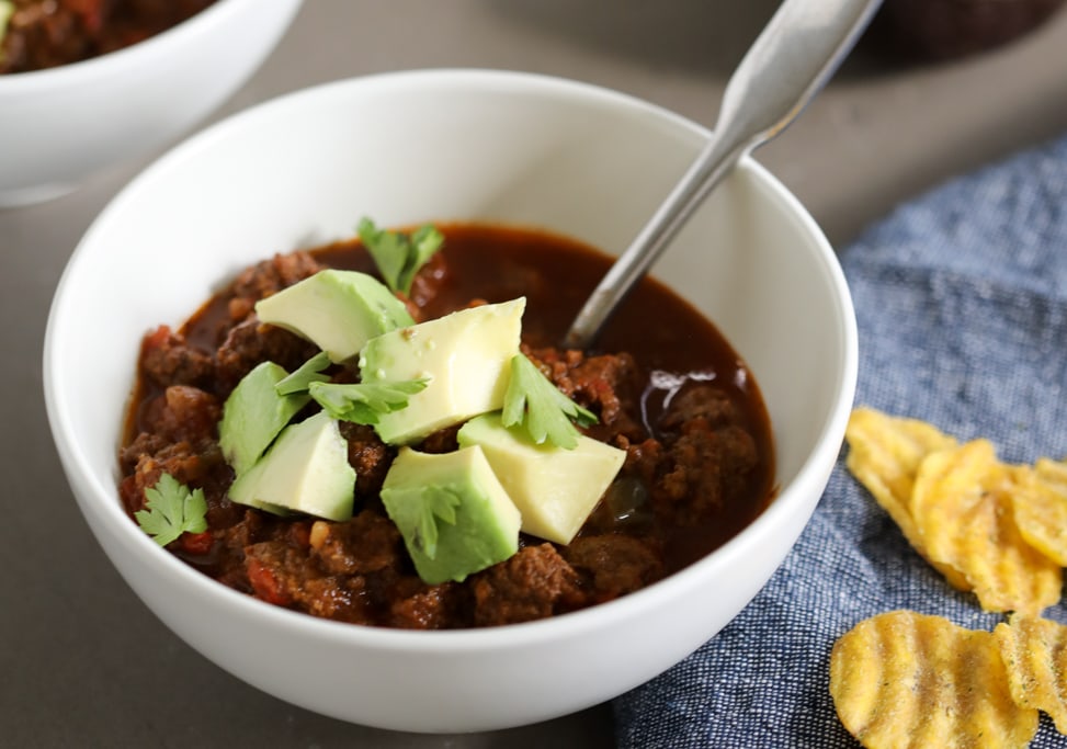 Instant Pot Option Chili Recipe with avocados on top in a bowl with cilantro and a spoon