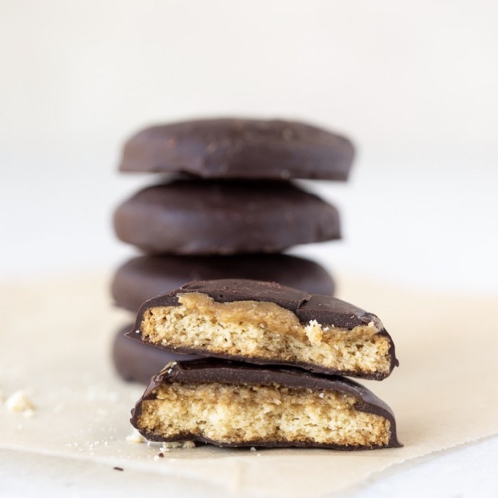 chocolate covered cookie (tagalong) cut in half for display with a stack of the same cookies blurred in the background