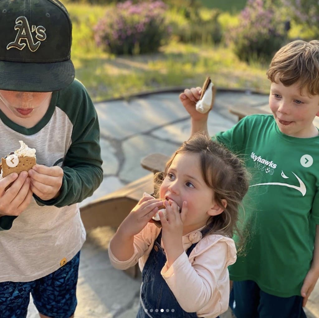 two young boys and one young girl delightfully enjoy their s'mores