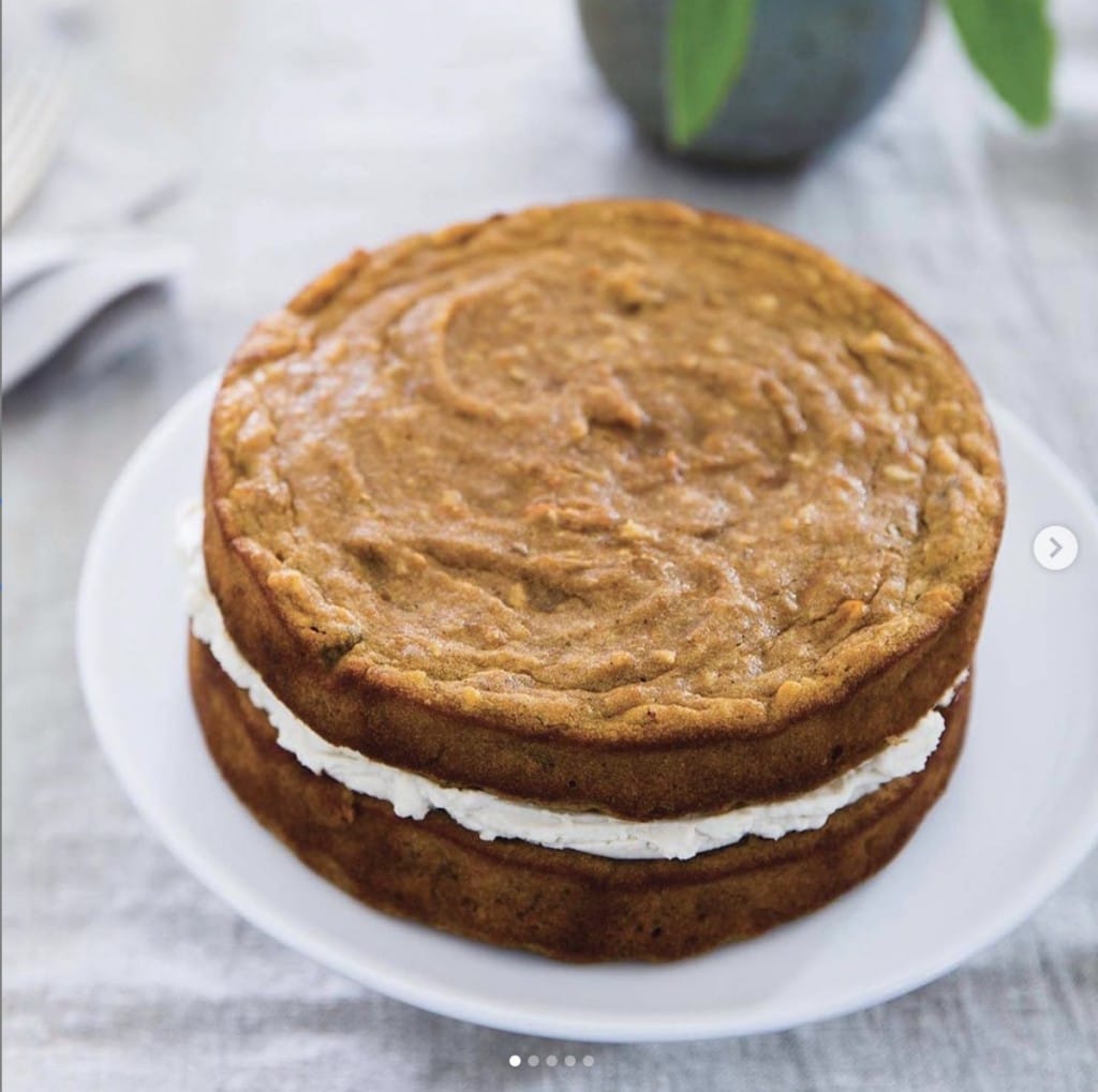carrot cake with a filling on a white plate displayed on gray table