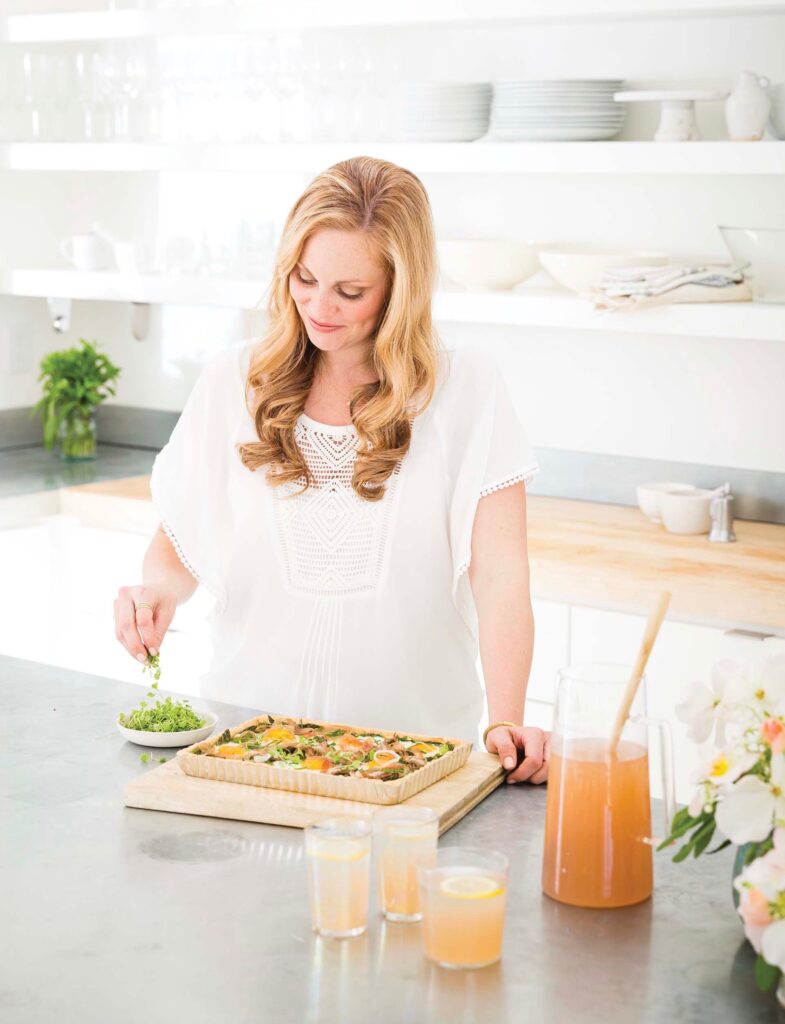 Pregnant woman stands in kitchen lovingly preparing a dish for her family and friends