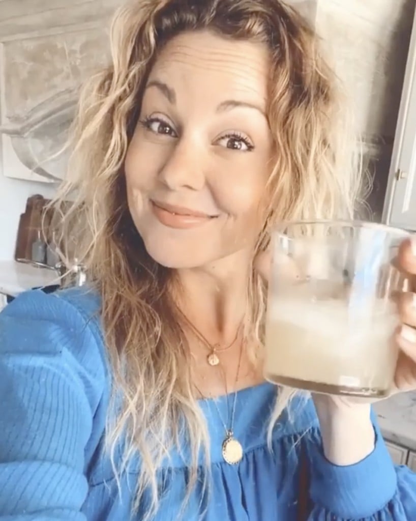 Smiling woman holds glass of margarita and smiles happily at camera
