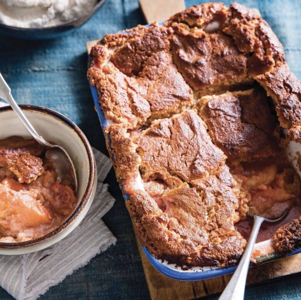 freshly baked peach cobbler being served into a bowl