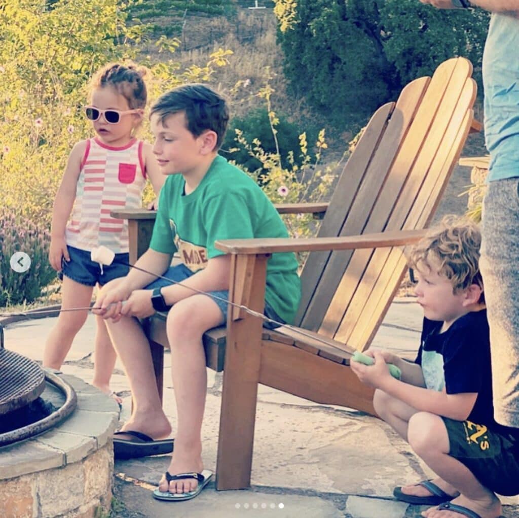 children gather around a stone fire pit to toast marshmallows